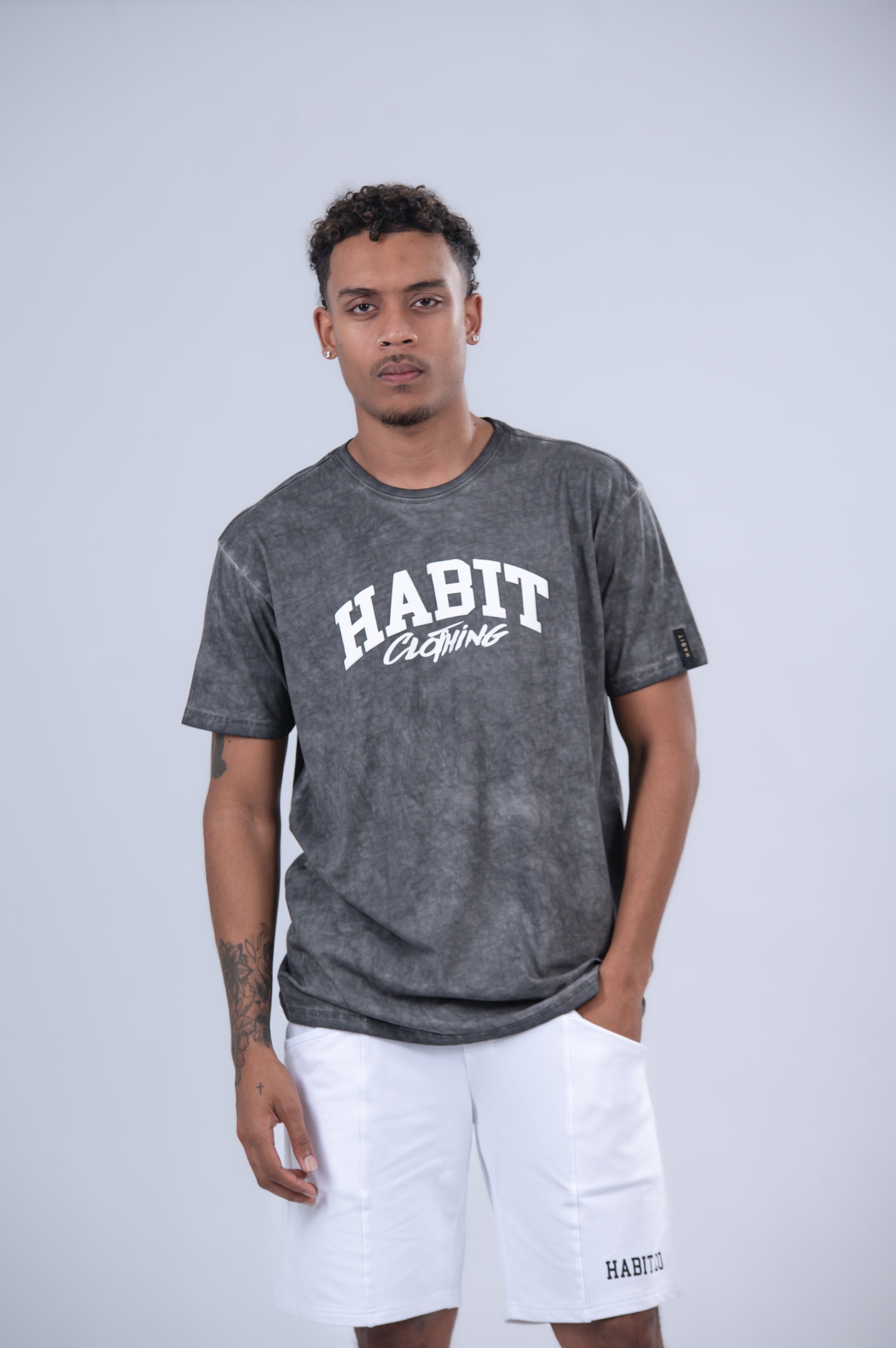 A man modeling a dark gray acid-wash t-shirt with 'HABIT Clothing' printed in white on the chest.