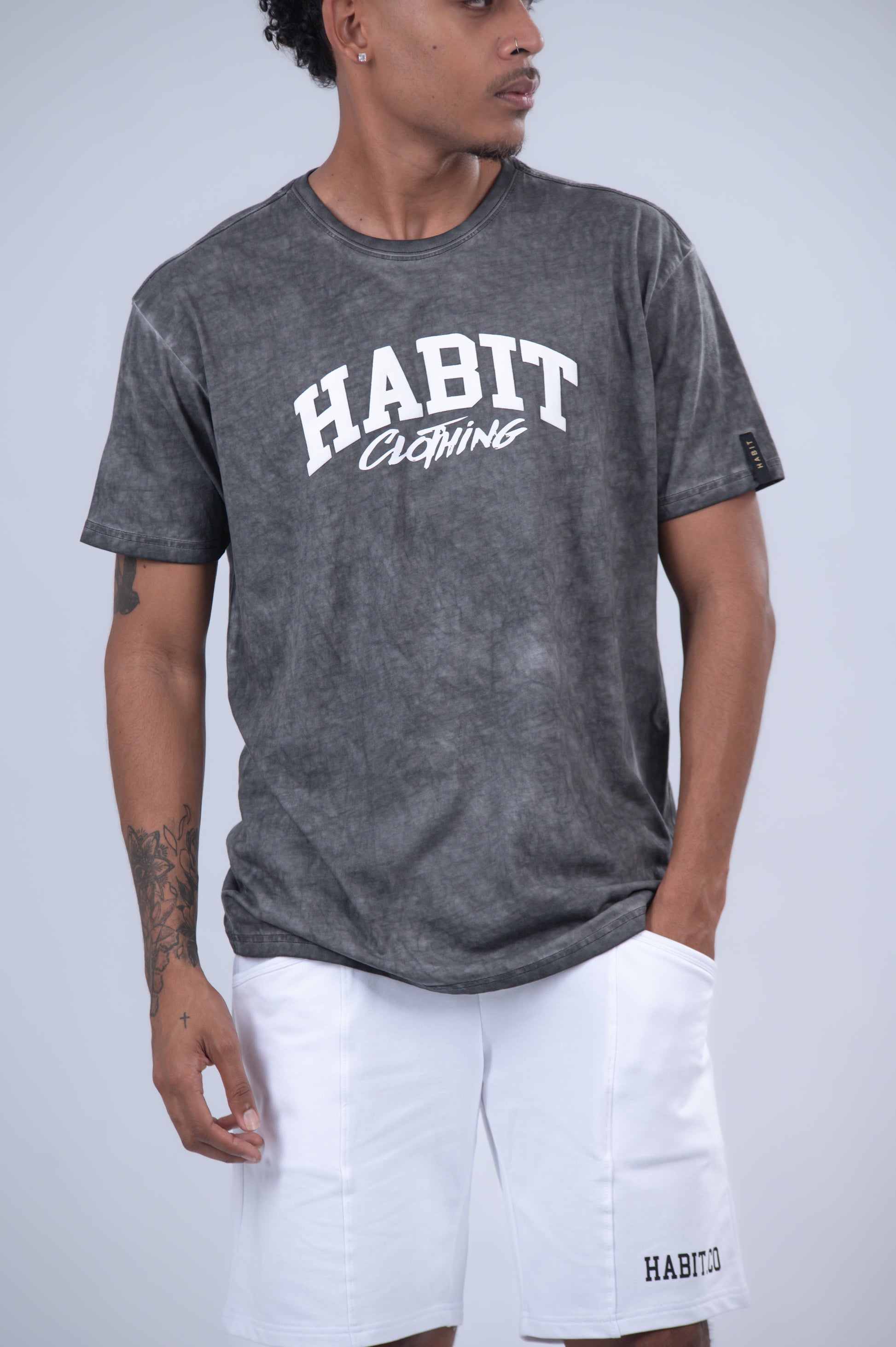 A man wearing a dark gray acid-wash t-shirt with 'HABIT Clothing' printed in white on the chest.